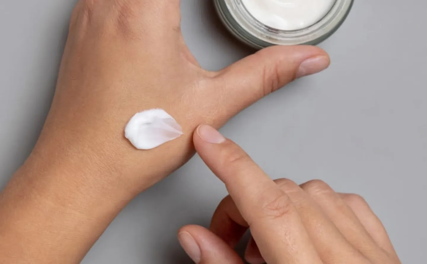 Applicering av vit hudkräm ansiktskräm på hand som tagits från en burk