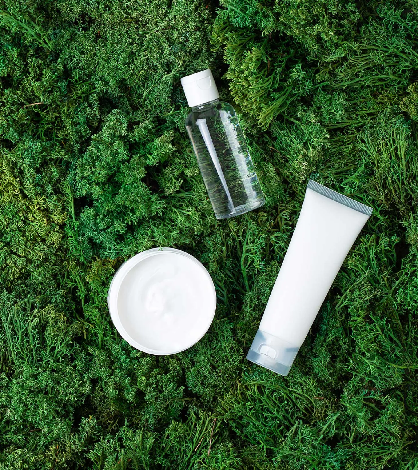 Hudvårdsprodukter uppställda mot växt grön matta
