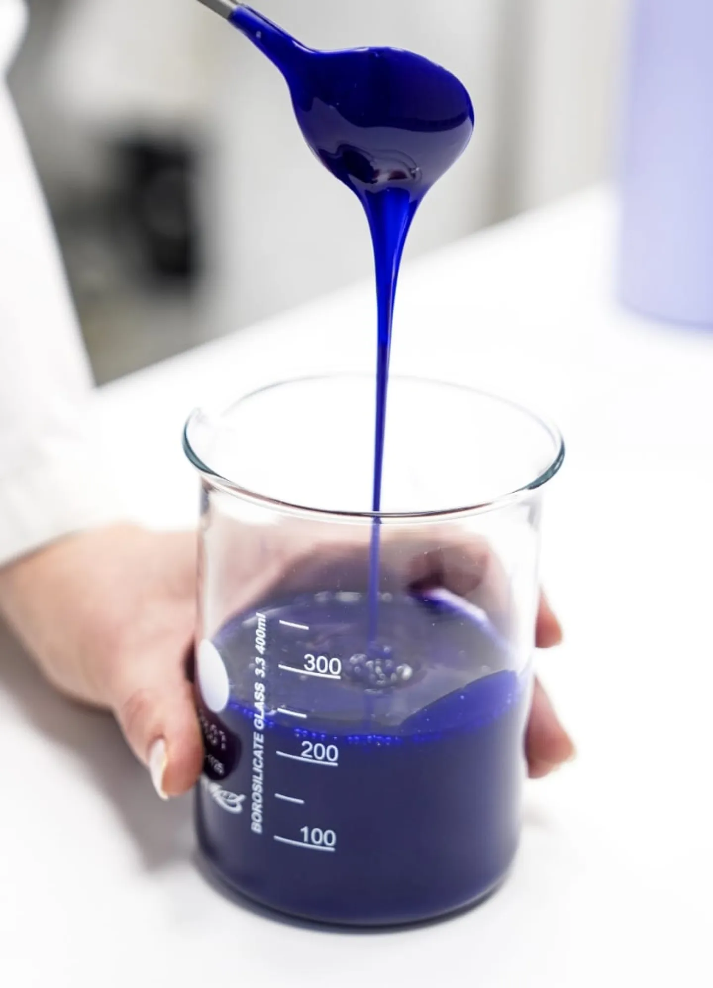 Produktutveckling blå vätska hälls från behållare i glas