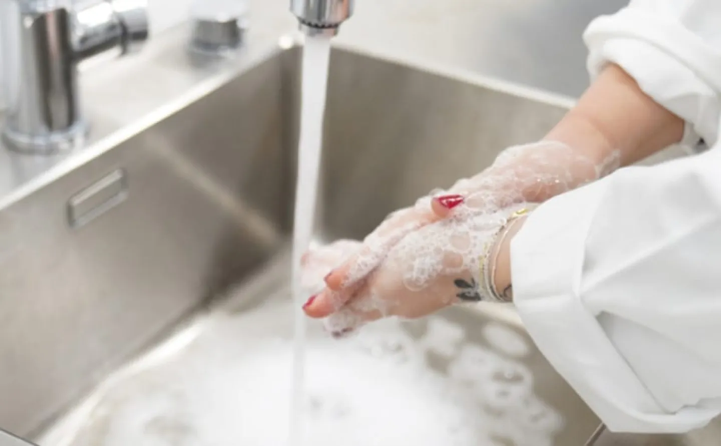 Handrengöring någon som tvättar sina händer i en vask