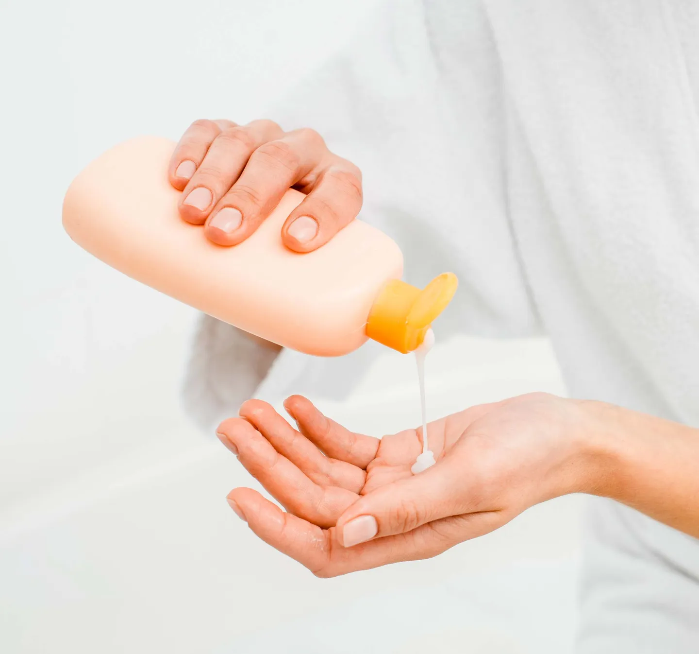 Bodylotion från orange rosa flaska hälls upp i hand
